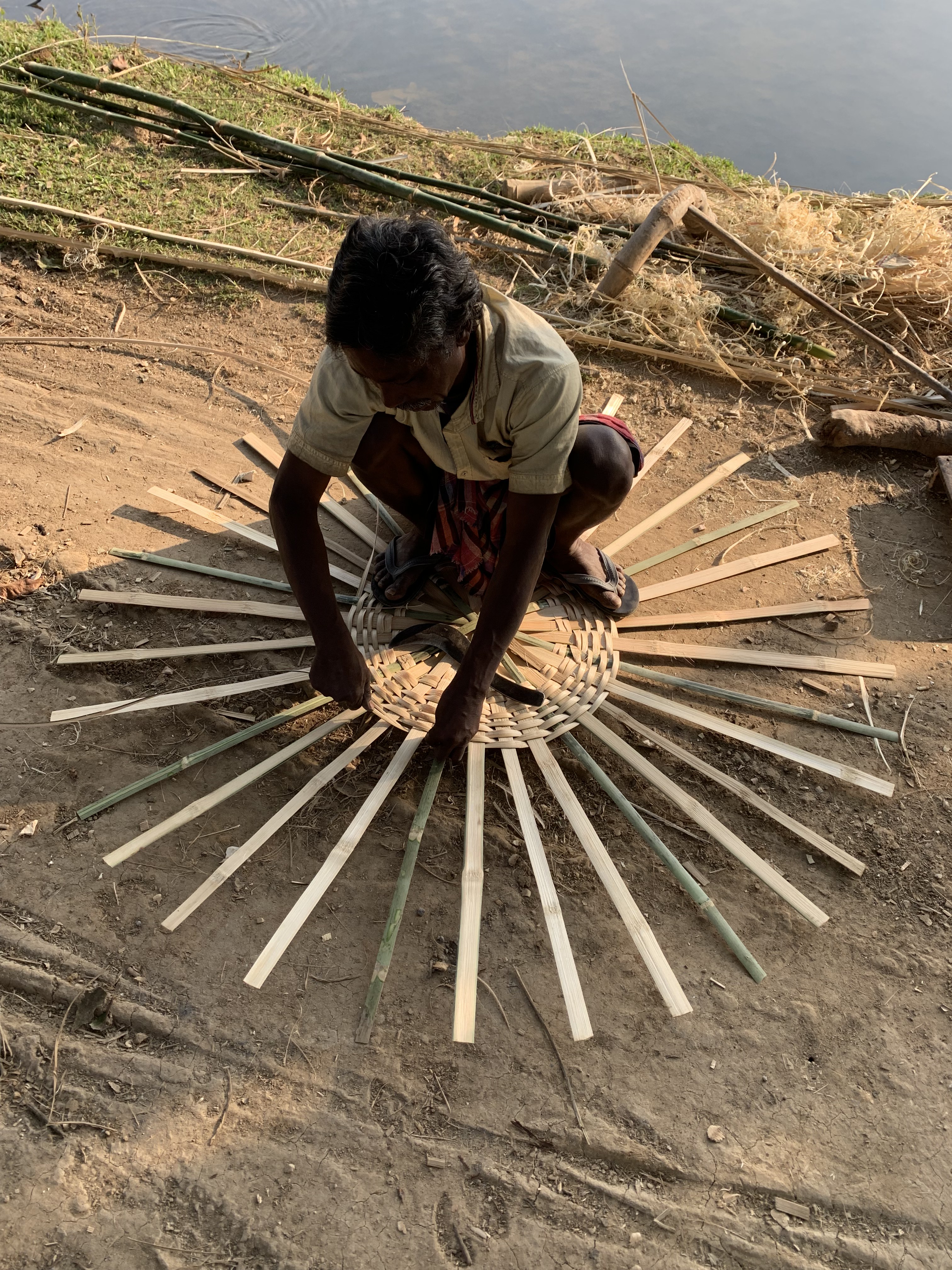 Bamboo craftsman weaving by the village pond